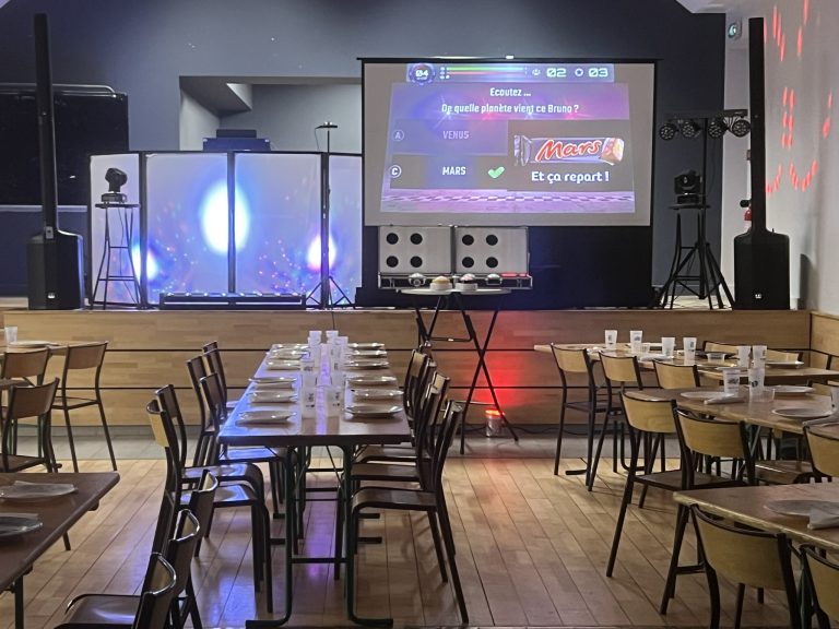 Salle équipée d'un écran géant et de tables prête pour un quiz animé