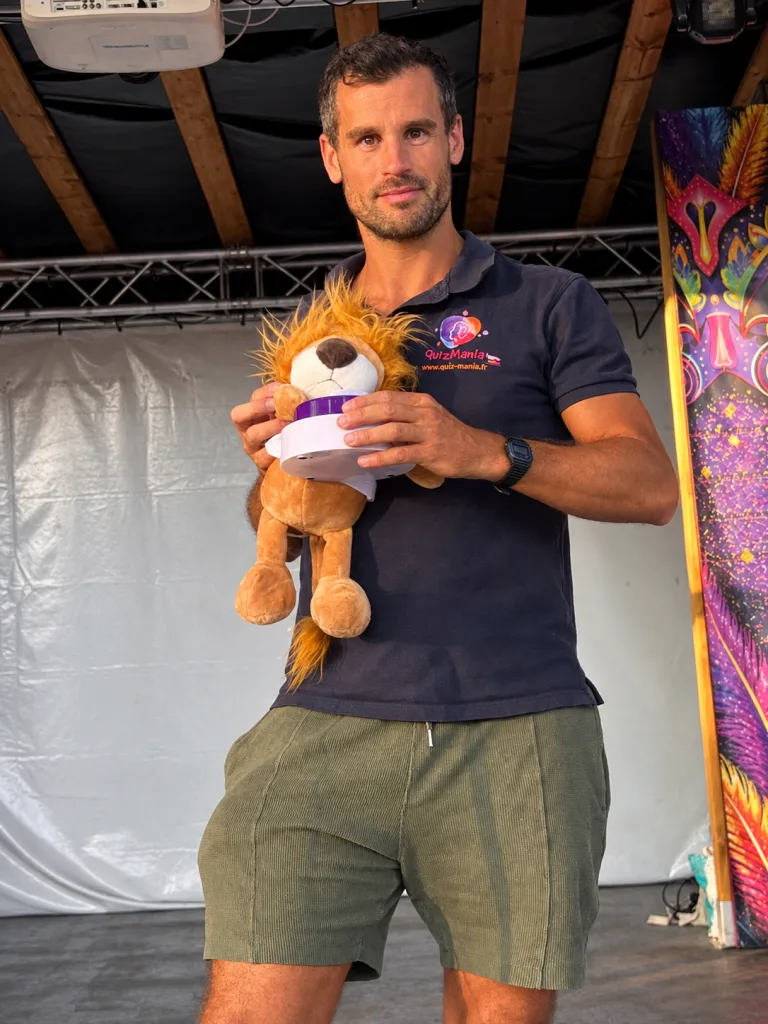 Animateur de L'Heure Bleue posant sur scène avec une peluche lion