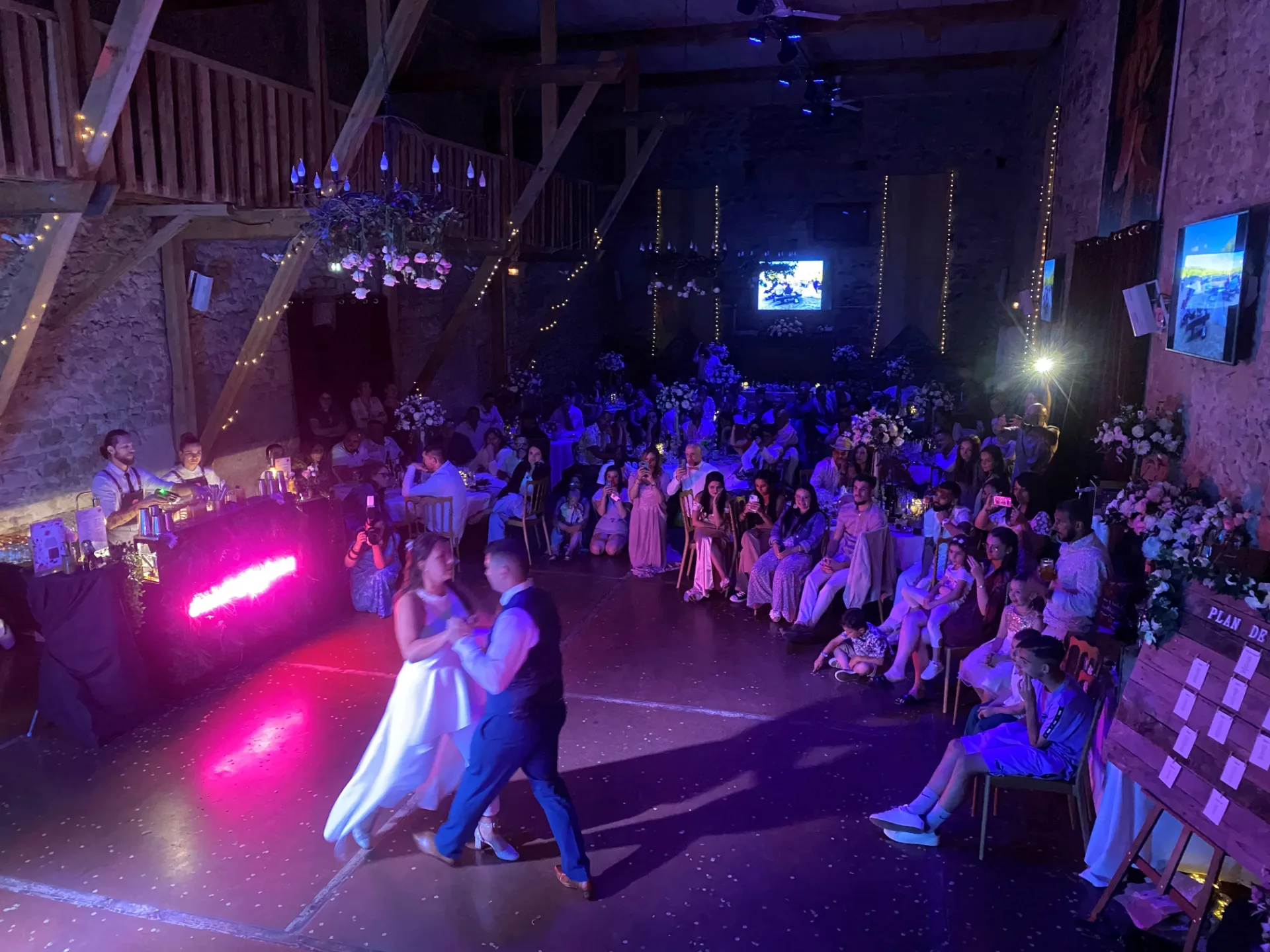 Ouverture de bal des mariés sur une piste illuminée, devant leurs invités dans une salle de réception en Auvergne