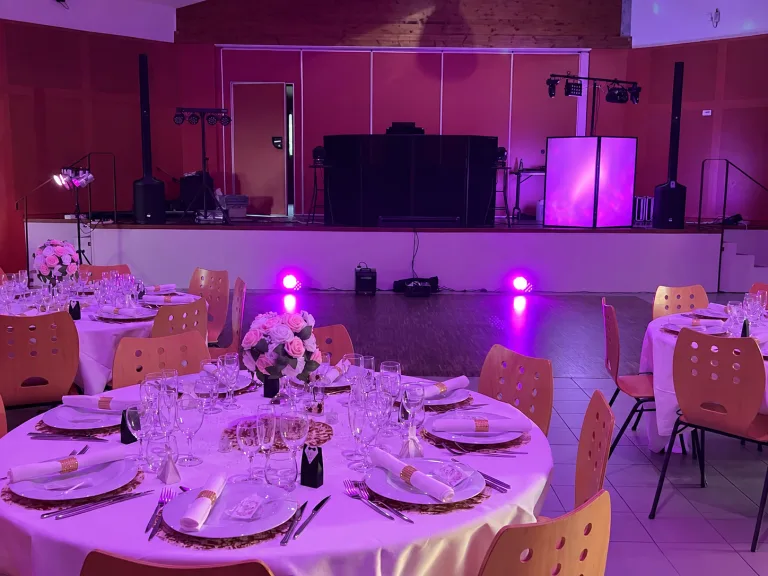 Salle de mariage dressée avec tables rondes et éclairage d'ambiance violet